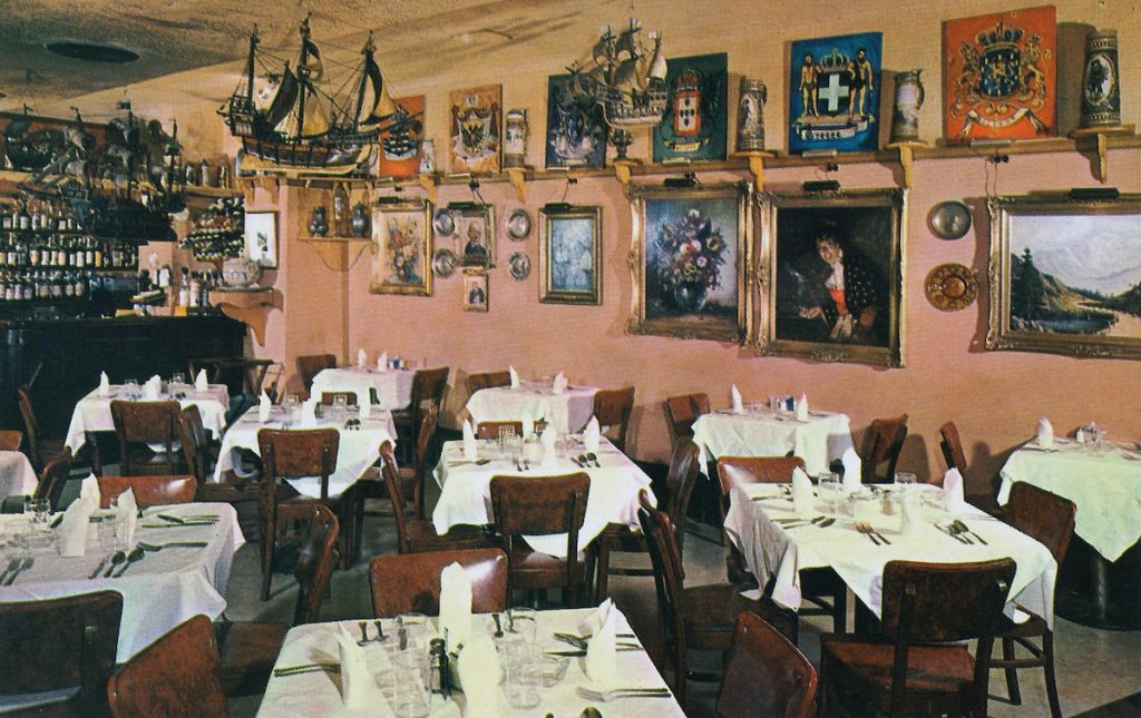 inside restaurant with many art pieces, paintings, ships, hanging on the walls above the tables