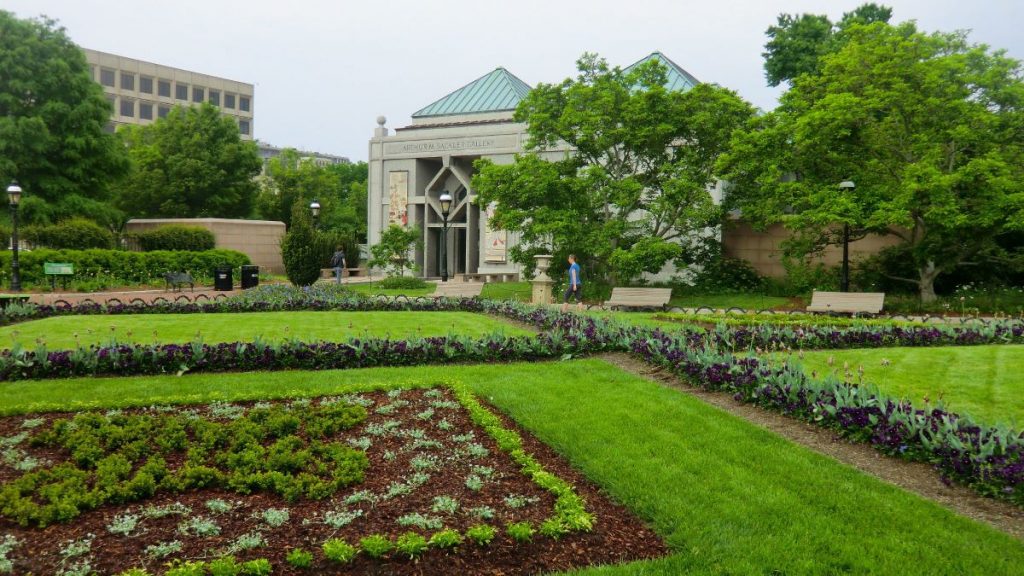 a beautiful green lawn with concrete building in the back.