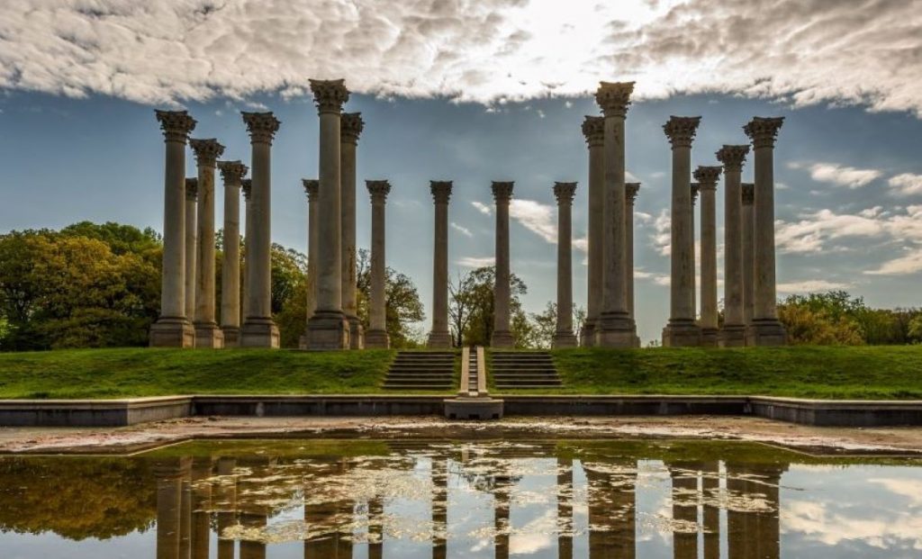 several columns placed in a circle behind a small body of water