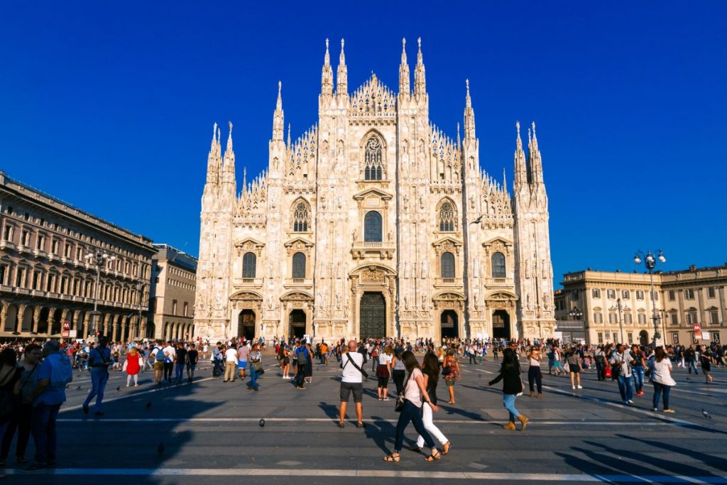 Hundreds of people gather in Piazza del Duomo, Milan, admiring the ornate Gothic facade and spires of Milan Cathedral.