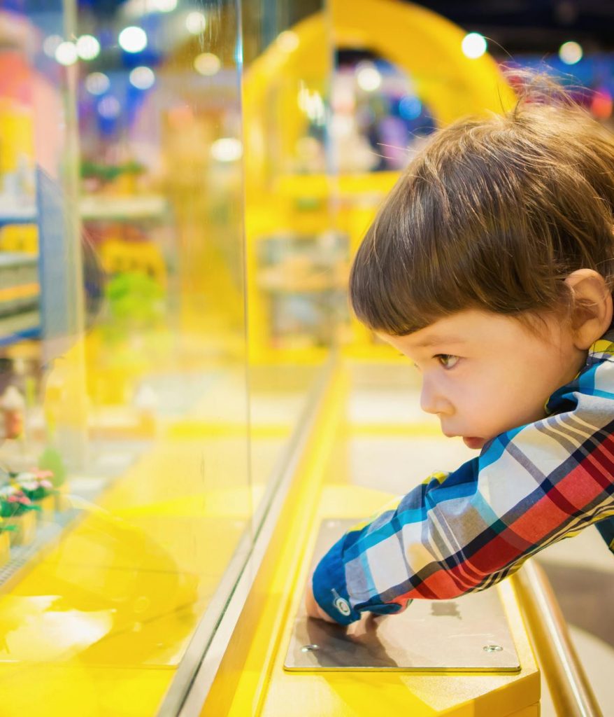 Child leaning over a toy display at one of the London attractions for families.
