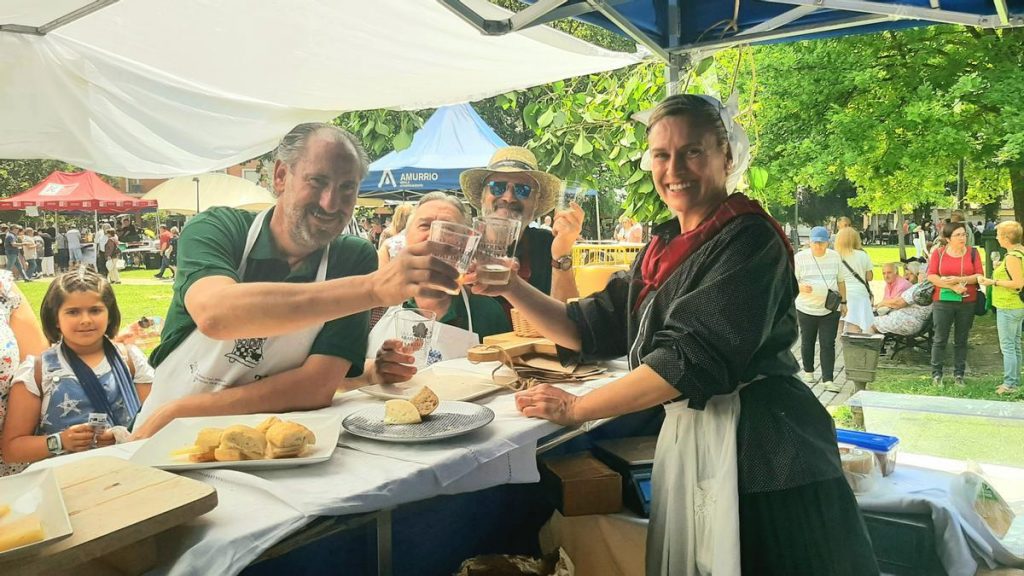Five adults and one child raise glasses in a cheerful toast at an outdoor food stall in San Sebastián, Spain.