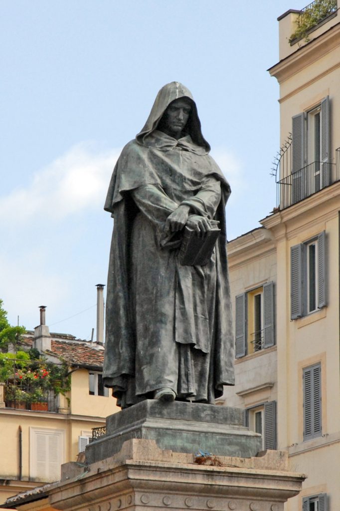 tall statue of a man with a hood holding a book
