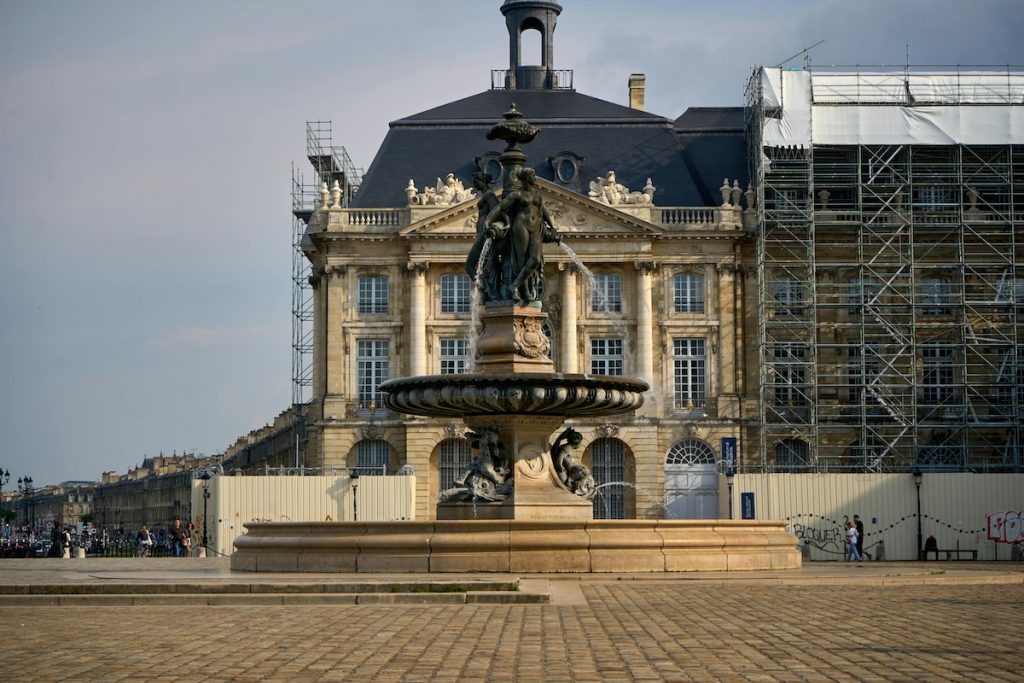 fountain with building and people in the back.