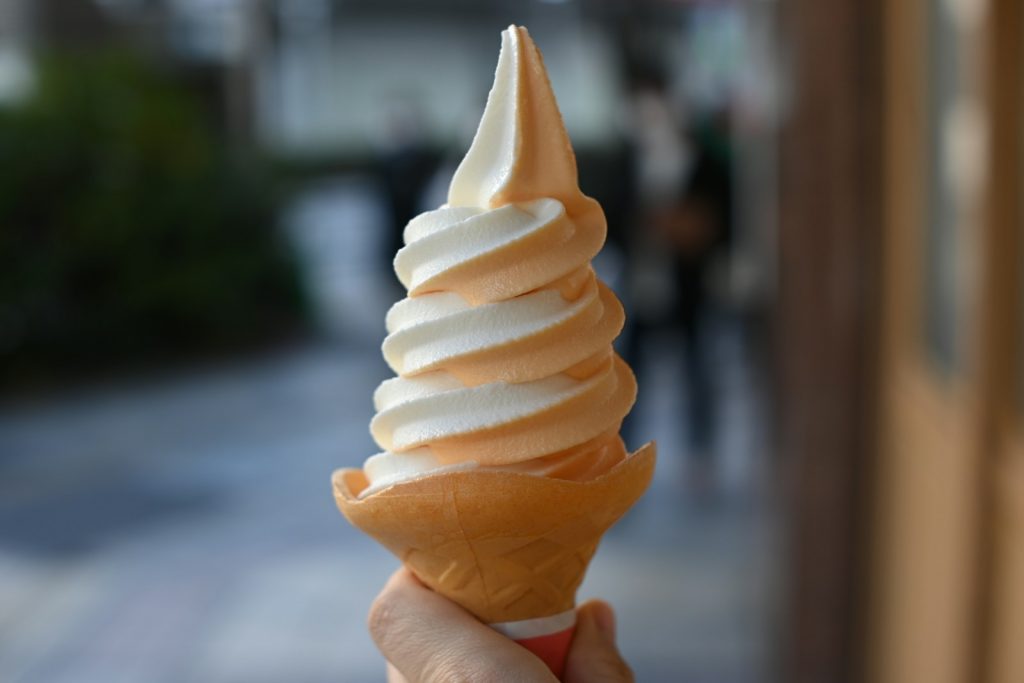 a hand holding an ice cream cone on a city street