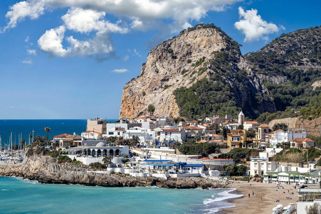 images of small seaside town with large cliffs in the background.
