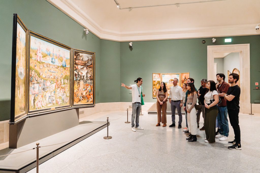 people gather around Hieronymus Bosch's The garden of Earthly Delights at the Prado Museum.