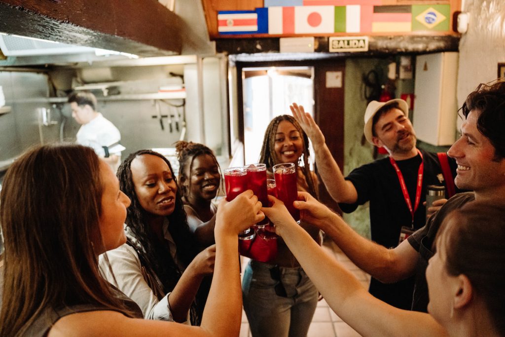 A group stands in a circle toasting with sanria inside a bar in Madrid