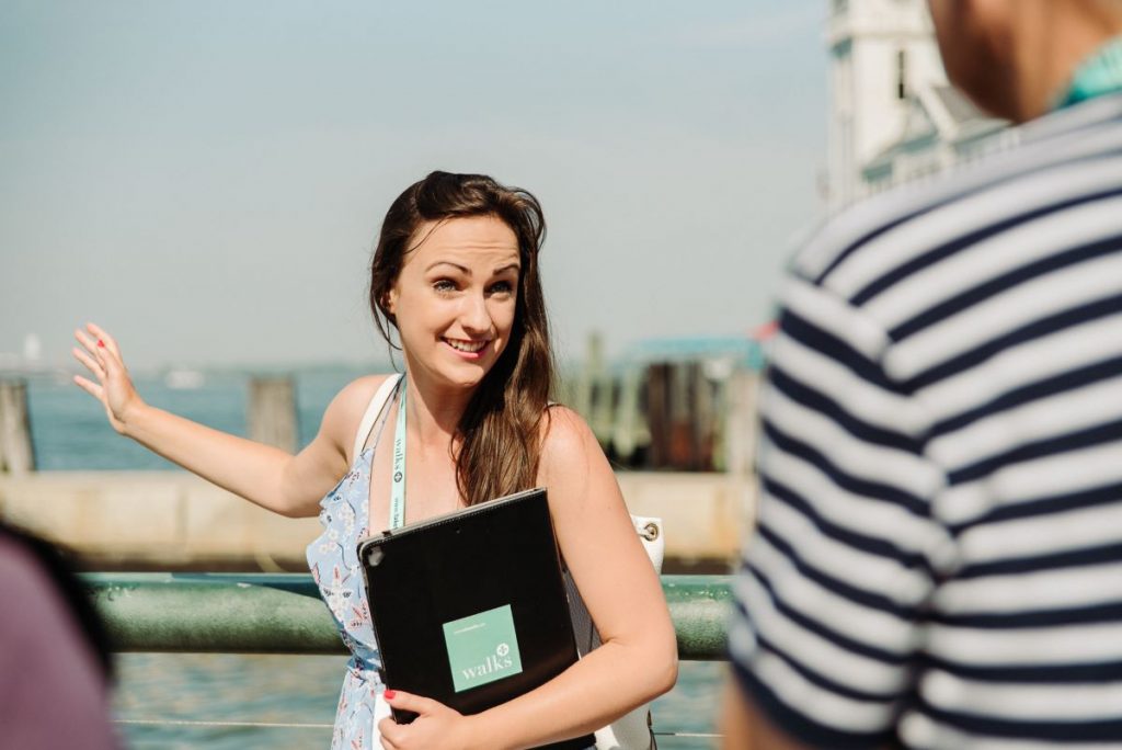 A woman holding a tablet is explaining a monument in Battery Park
