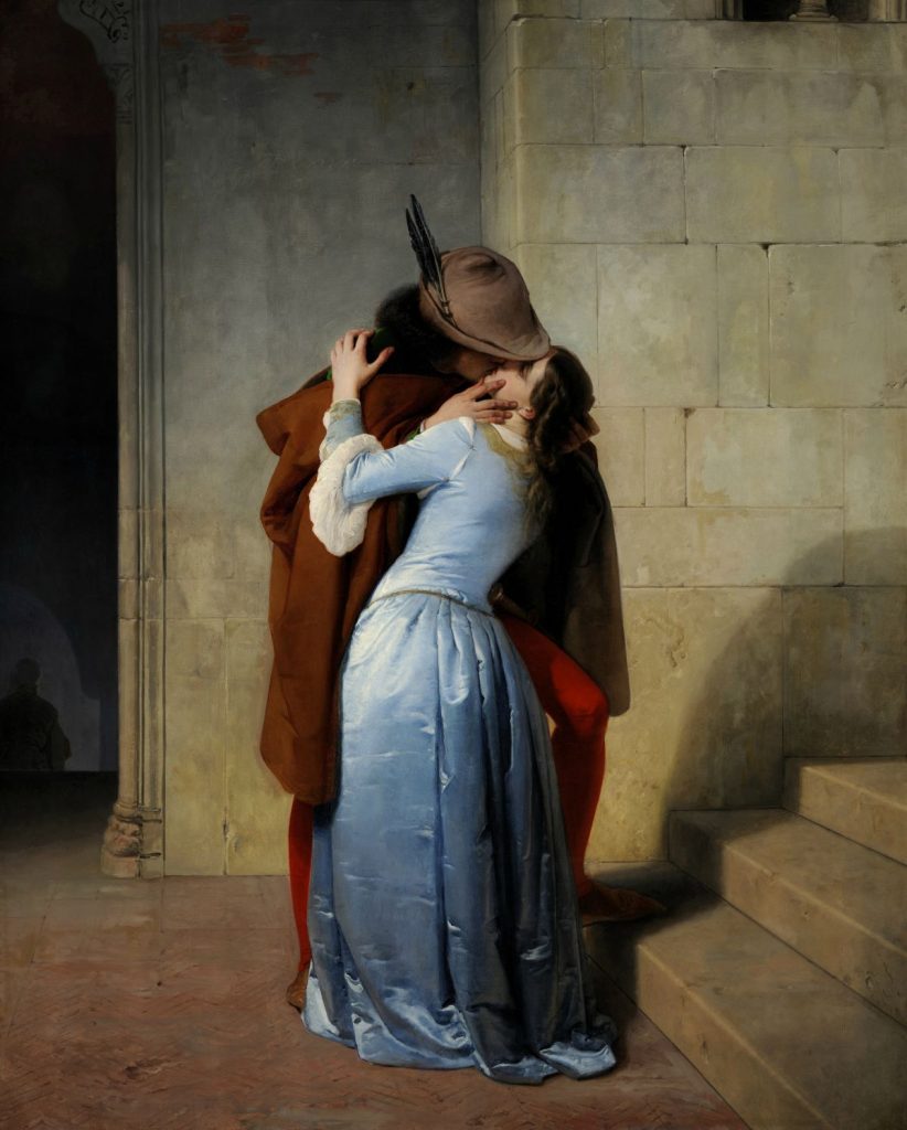 A man in a brown cloak kisses a woman in blue beside stone steps at the Pinacoteca di Brera in Milan, Italy.