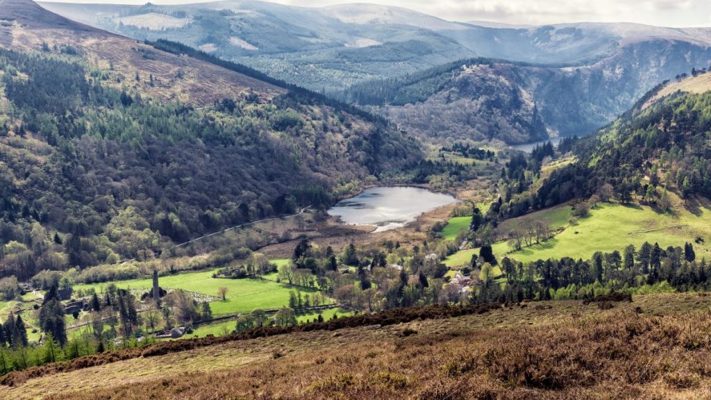 Scenic view of a green valley and lake on a day trip from Dublin to Glendalough.