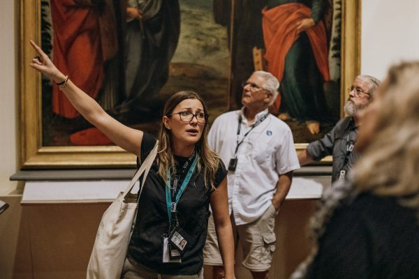 A museum guide points at Botticelli’s “The Birth of Venus,” explaining its significance to an attentive group in Florence’s Uffizi Gallery.