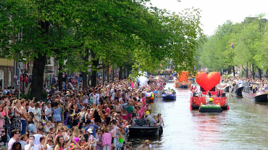A large group of people watching a boat float down a river