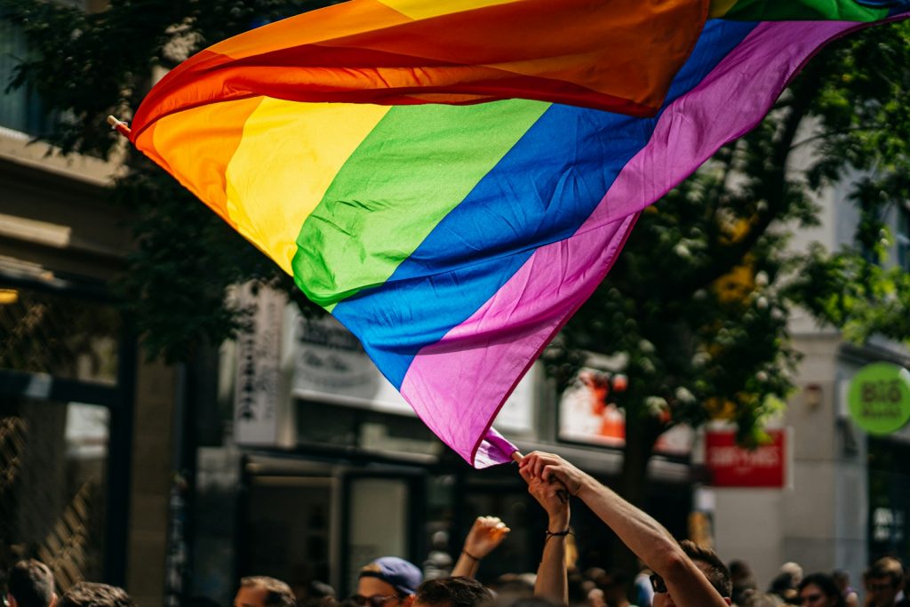 people holding a gay flag during daytime on the streets