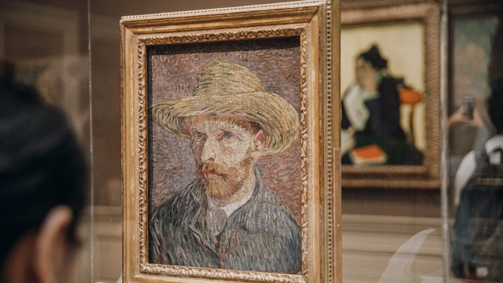 Vincent van Gogh’s “Self-Portrait” hangs at the Musée d’Orsay, with museum visitors and other artworks visible in the background.
