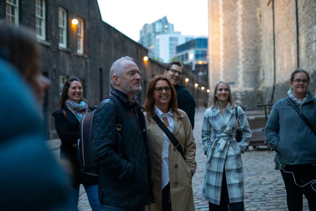 A cheerful group listens to a guide on a cobblestone street in Prague’s Old Town, surrounded by historic architecture.