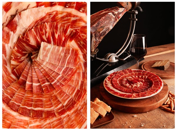 Thinly sliced cured ham spirals left; right side shows red wine, bread, and a full ham leg on a rustic table setting. 