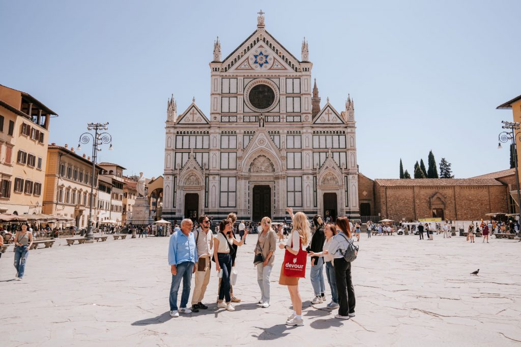 Tourists stand and chat before the Basilica di Santa Croce’s ornate facade in Florence’s spacious, sunny square, as part of an overnight trip from Rome.