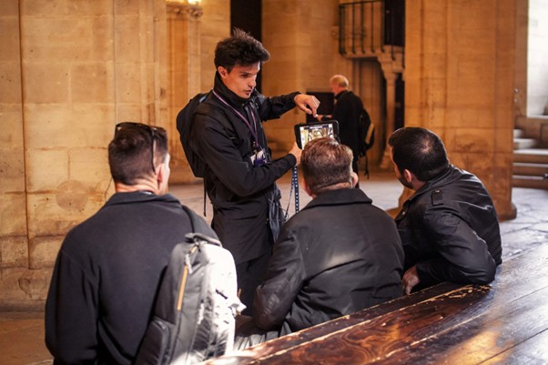 A tour guide shows three visitors a tablet, explaining one of the stories behind the building and its features